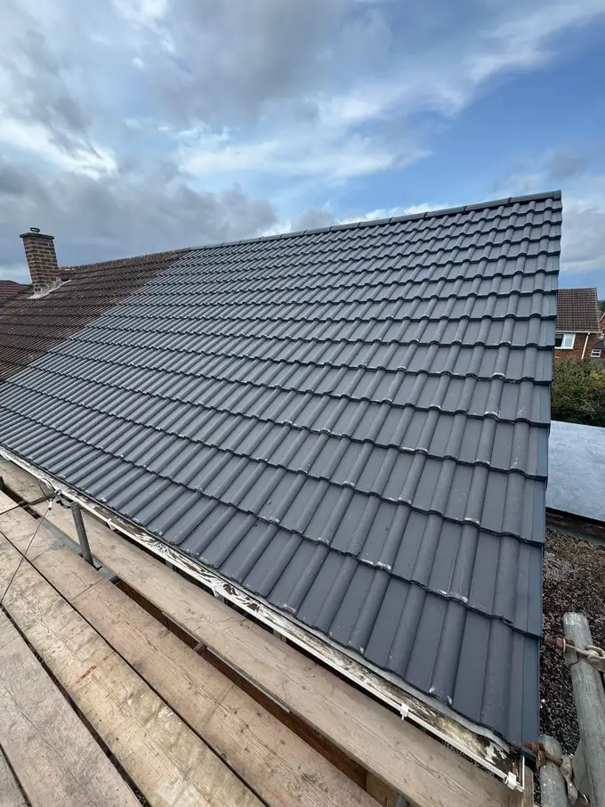 New grey interlocking tiles on a pitched roof under a blue sky