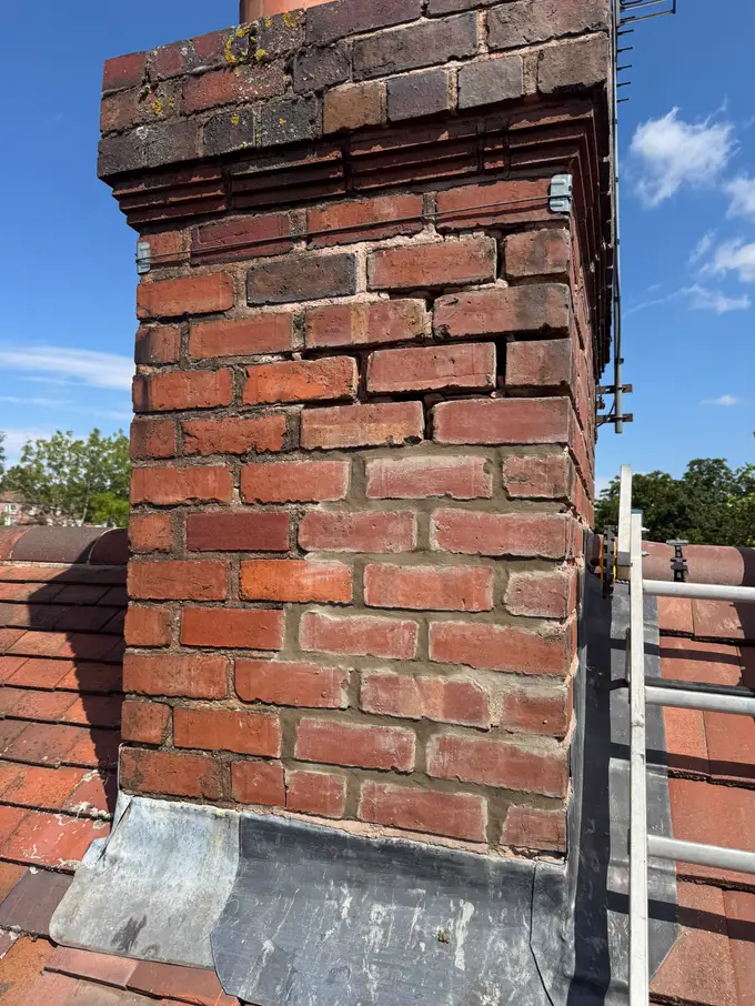 Freshly repointed chimney stack with new mortar joints, a roof ladder alongside